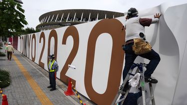 Obreros colocan logos en una barrera frente al Estadio Nacional, sede de la ceremonia de apertura y otras competencias de los aplazados Juegos Olímpicos de Tokio, el miércoles 2 de junio de 2021