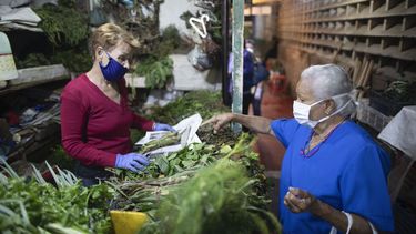 En esta foto del 20 de marzo de 2020, una mujer, con una mascarilla protectora, compra hierbas frescas en un mercado en Caracas, Venezuela.&nbsp;