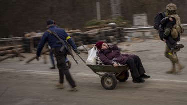 Un soldado ucraniano y un miliciano ayudan a una familia que huye a cruzar el río Irpin en las afueras de Kiev, Ucrania, el sábado 5 de marzo de 2022.&nbsp;