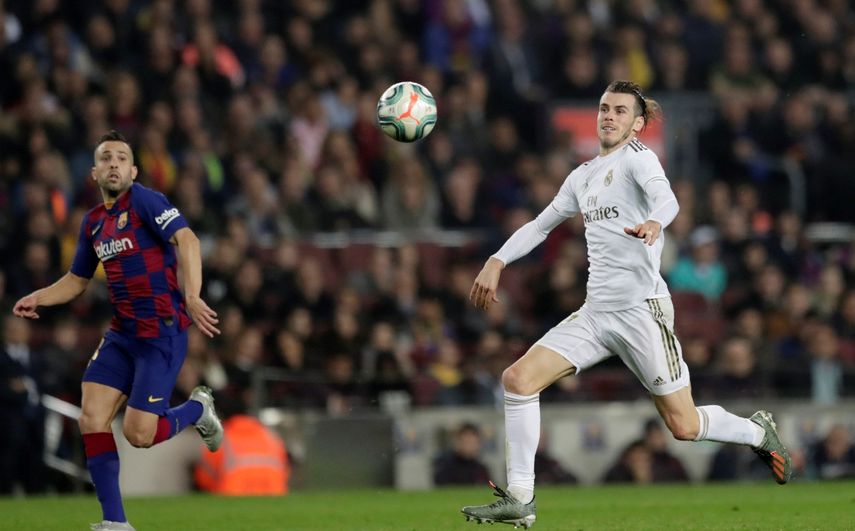 Gareth Bale, derecha, del Real Madrid, va tras el bal&oacute;n ante la marca de Jordi Alba, del Barcelona, en el cl&aacute;sico de La Liga en el Camp Nou de Barcelona, el mi&eacute;rcoles 18 de dociembre de 2019.