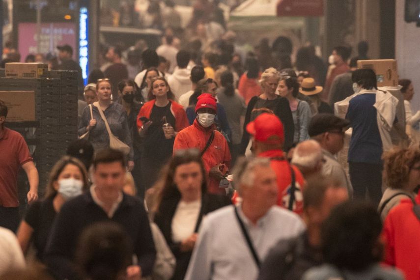 Algunas personas utilizan mascarillas mientras recorren el exterior de la plaza Herald invadida por humo en Nueva York, el miércoles 7 de junio de 2023.