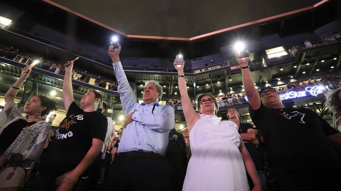 Gente sostiene sus celulares al leerse los nombres de los fallecidos en el tiroteo del 3 de agosto en una ceremonia de recuerdo a las víctimas en el Southwest University Park, en El Paso, Texas, el 14 de agosto de 2019.&nbsp;