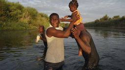 Hombres cargan a una niña a través del Río Bravo mientras los migrantes, muchos de Haití, abandonan Del Río, Texas, para regresar a Ciudad Acuña, México, el miércoles 22 de septiembre de 2021 temprano, algunos para evitar una posible deportación de EEUU otros a conseguir suministros