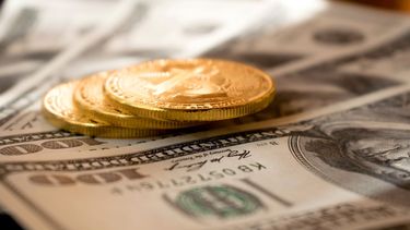 Imagen de criptomonedas y billetes de 100 dólares.
