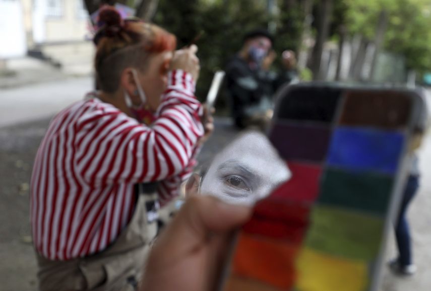 Integrante de la compa&ntilde;&iacute;a de circo se refleja en un pedazo de espejo mientras se prepara para una presentaci&oacute;n en la calle en la que su grupo conocido como Circo Encuentro act&uacute;a a cambio de donaciones de alimentos para ayudar a personas de bajo recursos en Bogot&aacute;, Colombia, el s&aacute;bado 4 de julio de 2020.&nbsp;