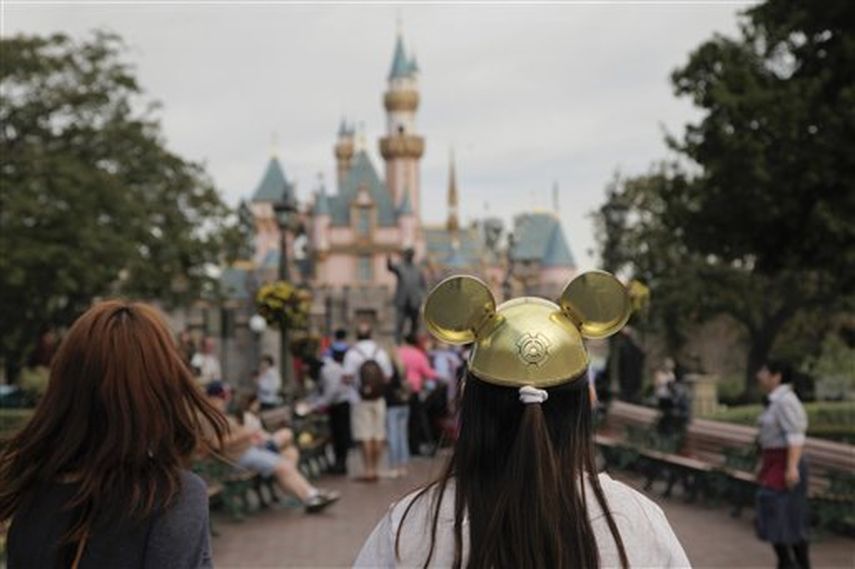 Una mujer con un gorro de Mickey Mouse camina hacia el Castillo de la Bella Durmiente en Disneyland. (AP)