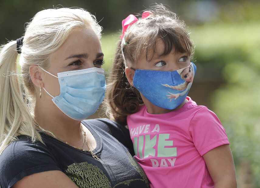 Madre e hija usan mascarillas al entrar al zoológico de Miami.