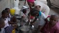 Una mujer acompañada de niños cocina en el refugio para familias desplazadas por la violencia de las pandillas en Puerto Príncipe, Haití, el jueves 9 de diciembre de 2021.