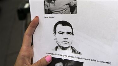 Un periodista sostiene un retrato de Antonio Jaime Stiuso, un enigmático jefe de inteligencia argentino, frente a la oficina del fiscal en Buenos Aires. AP 