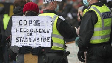 Una activista por el clima sostiene un cartel junto a policías cerca de la sede de la Conferencia de Naciones Unidas sobre Cambio Climático, o COP26, en Glasgow, Escocia, el 12 de noviembre de 2021.&nbsp;
