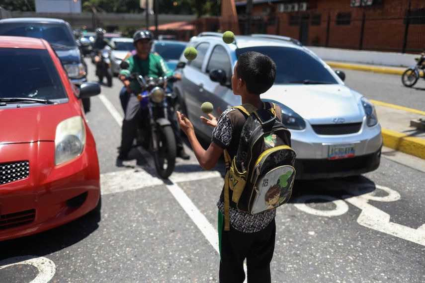 Un niño hace malabares en plena avenida del centro de Caracas para buscar algún dinero.&nbsp;