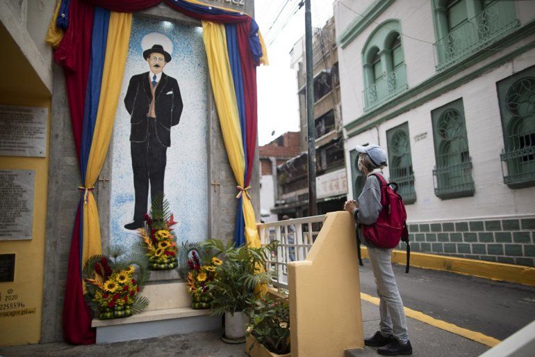 Una mujer reza cerca de un cuadro con la imagen de JosÃ© Gregorio HernÃ¡ndez en la calle en la que falleciÃ³ en un accidente de auto en 1919, en el vecindario de La Pastora, en Caracas, Venezuela, el 28 de abril de 2021. Conocido como el 