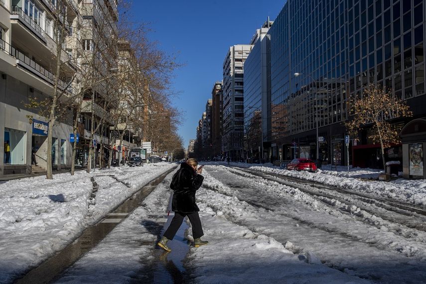 Una mujer cruza una calle nevada en Madrid, España, 11 de junio de 2020. La capital española trata de volver a ponerse en marcha tras una nevada récord que paralizó una gran parte del centro del país.&nbsp;
