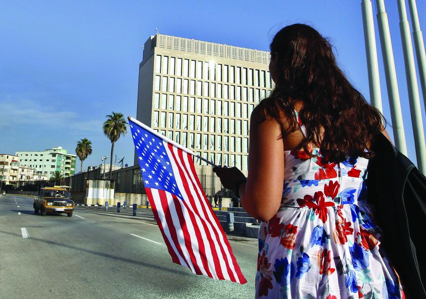 Una mujer camina con una bandera de EEUU frente a la embajada de ese país en La Habana, el día de la apertura de esa sede diplomática, el 20 de julio de 2015.