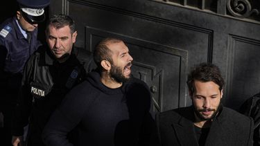 Policías escoltan al influencer Andrew Tate esposado a su hermano Tristan, derecha, de la Corte de Apelaciones después de apelar el fallo para extender su arresto otros 30 días en Bucarest, Rumania, el miércoles 1 de febrero de 2023.