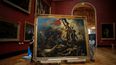 Los trabajadores de la galería retiran la pintura La libertad guiando al pueblo de Delacroix (1798-1863) de sus rieles en el Museo del Louvre en París el 20 de septiembre de 2023.