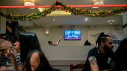 Personas cenan en un restaurante mientras el presidente Javier Milei emite un mensaje televisado anunciando nuevas medidas económicas,