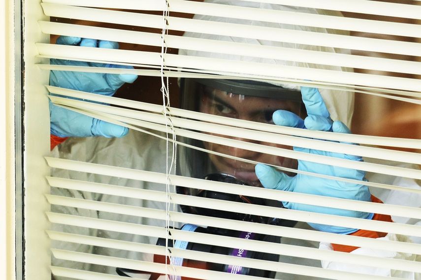 Un trabajador vestido con un equipo de protecci&oacute;n y un respirador mira por una ventana mientras espera para salir del Life Care Center en Kirkland, Washington, luego de desinfectar la residencia de ancianos, el 11 de marzo de 2020.