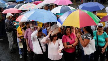 Personas hacen fila en medio de una fuerte lluvia para votar en las elecciones primarias de la oposición en Caracas, Venezuela, el domingo 22 de octubre de 2023.