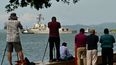 La gente observa y toma fotos del USS Gravely, un barco de guerra de la Marina de los Estados Unidos, al salir del Puerto de Puerto España el 30 de octubre de 2025.
