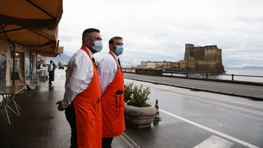 Dos empleados de un restaurante esperan por turistas en Nápoles, Italia.