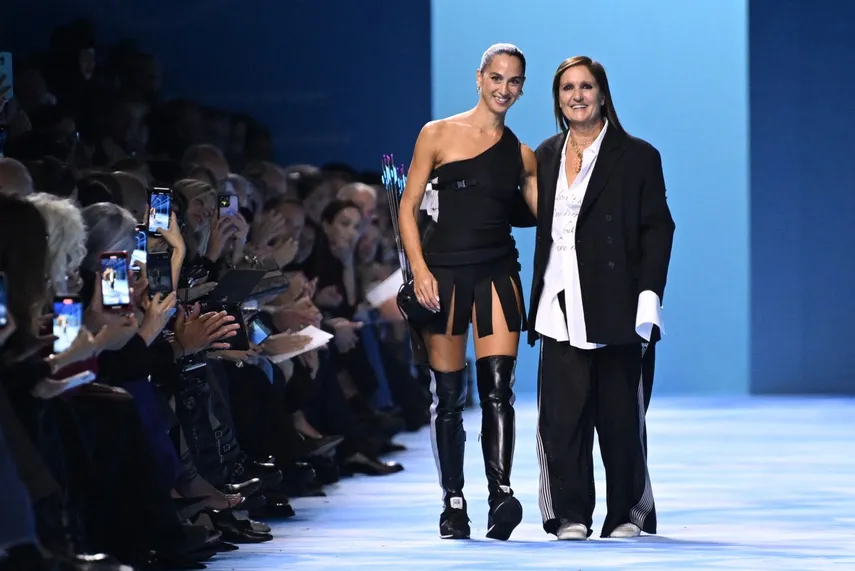 La diseñadora de moda italiana Maria Grazia Chiuri saluda a la audiencia con la artista italiana Sagg Napoli después de la presentación de Dior de la colección de prêt-à-porter femenino primavera-verano 2025 como parte de la Semana de la Moda de París, en París el 24 de septiembre de 2024. 