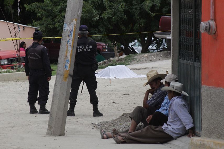Policías estatales mexicanos custodian los cuerpos de las víctimas de un grupo armado que irrumpió en la localidad de Huehuetlán el Grande, en Puebla, el 3 de julio de 2017.&nbsp;