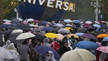 Personas con impermeables y paraguas caminan por una plaza cerca de la entrada de Universal Studios Beijing en Beijing, el 20 de septiembre de 2021. Miles de personas asistieron a la inauguración del parque temático a pesar de la lluvia. AP/Andy Wong