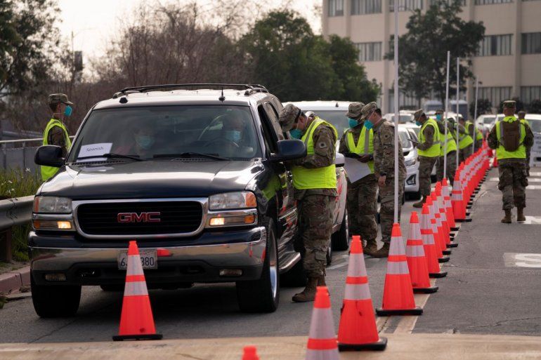 Miembros de la Guardia Nacional ayudan a personas que llegan en sus automóviles a vacunarse contra el COVID-19.