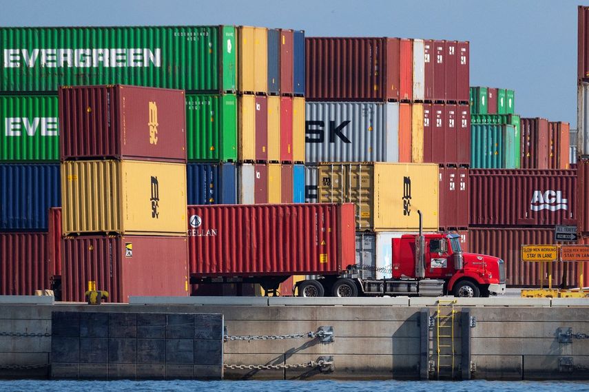 Un chofer de rastra sale del puerto con un contenedor.