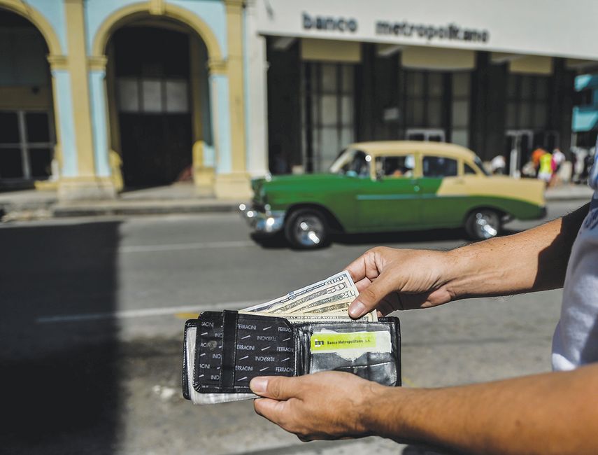 Un hombre muestra varios billetes de dólar en una calle en La Habana .
