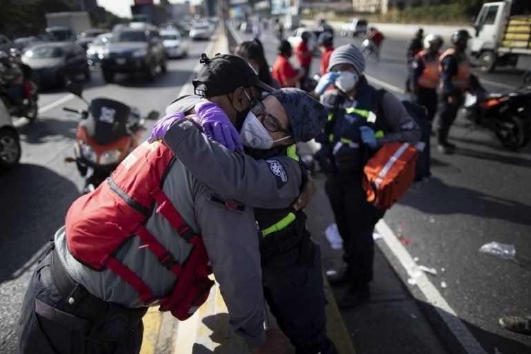 La socorrista voluntaria Zully Rodiz (der) abraza a un socorrista de los servicios públicos en el lugar de un accidente de tráfico en Caracas el 10 de febrero del 2021. Rodiz asegura que no hay rivalidad entre los dos servicios y que, por el contrario, colaboran entre ellos.