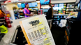 Una persona sostiene un ticket del Mega Millions.