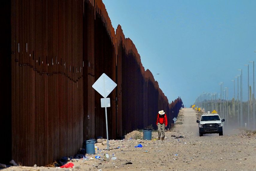 El profesor de escuela retirado Tom Wingo, del grupo Samaritanos Sin Frontera, camina lo largo del muro fronterizo al tiempo que un agente de la Patrulla Fronteriza de Estados Unidos patrulla el área, el martes 29 de agosto de 2023, cerca de Lukeville, Arizona. 