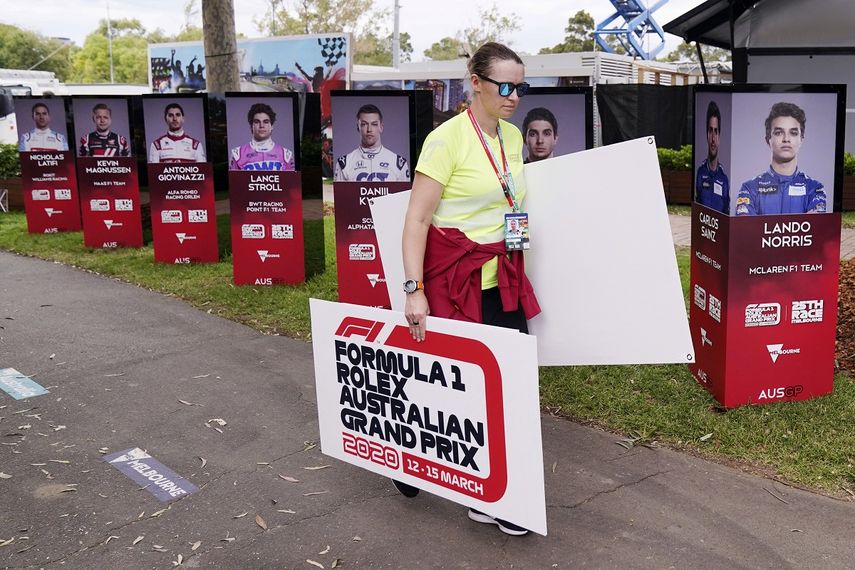 Una mujer retira carteles tras la cancelación del Gran Premio de Australia de Fórmula&nbsp;1 en Melbourne, el viernes 13 de marzo de 2020, debido al brote de coronavirus.