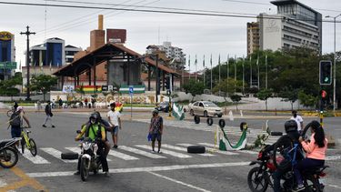 Motociclistas y peatones pasan por una calle bloqueada durante una huelga indefinida convocada por sindicatos opuestos al gobierno del presidente boliviano Luis Arce en Santa Cruz, Bolivia. El departamento boliviano de Santa Cruz, gobernado por la oposición, el motor económico del país, se paralizó el sábado al inicio de una protesta indefinida para exigir al gobierno de izquierda del presidente Luis Arce que adelante un año el censo de población fijado para 2024.