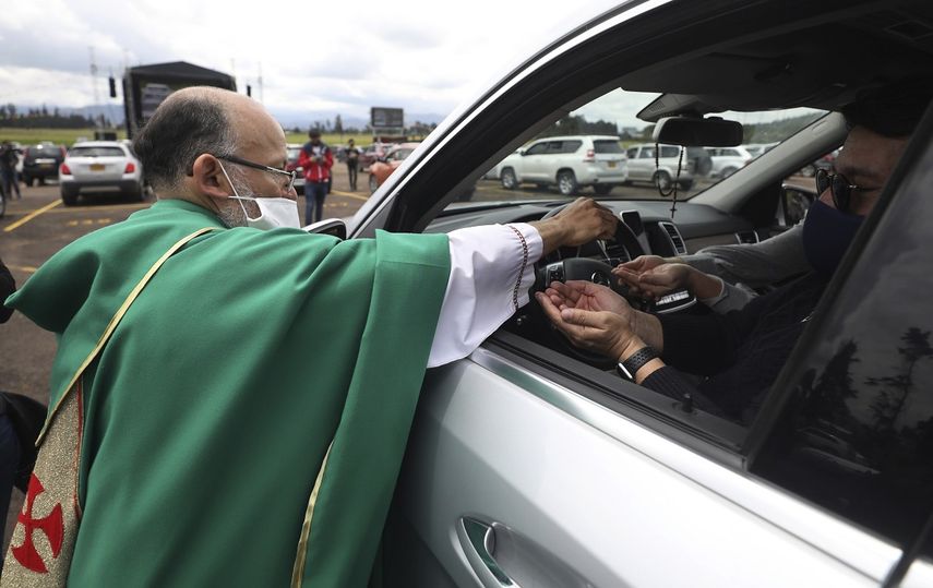 El sacerdote cat&oacute;lico Luis Carlos Ayala, con una mascarilla para protegerse del coronavirus, entrega la comuni&oacute;n a los fieles el domingo 30 de agosto de 2020 durante una misa, en Chia, Colombia.&nbsp;