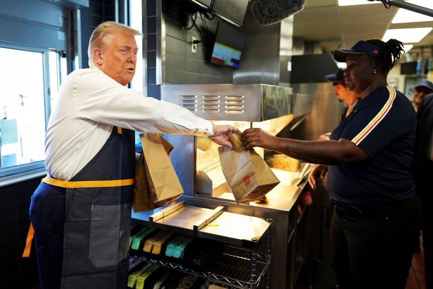 Un empleado entrega una orden al candidato presidencial republicano, el expresidente Donald Trump, durante una visita a un McDonalds, el domingo 20 de octubre de 2024, en Feasterville-Trevose, Pennsylvania.