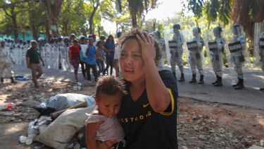 Una migrante con un niño en brazos se aleja de agentes de la Guardia Nacional que bloquean el paso a un grupo de migrantes centroamericanos, el jueves 23 de enero de 2020, en Tapachula, México.