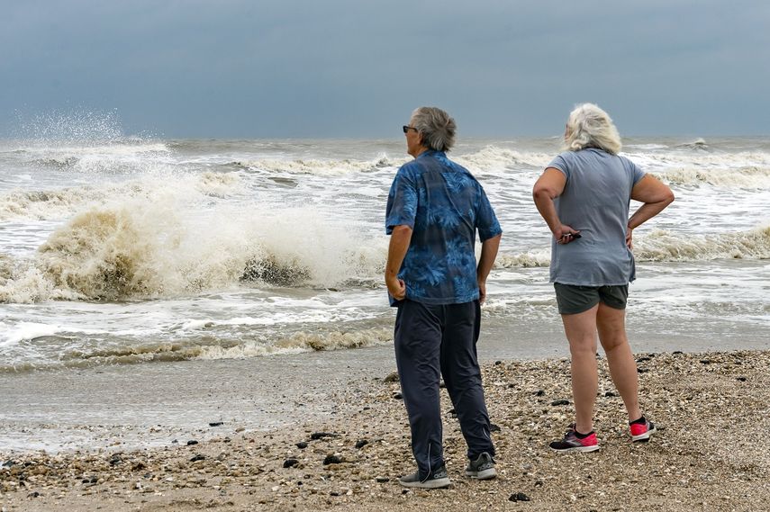 Steve y Linda Buser, de Beaumont, miran el fuerte oleaje en la playa junto al cruce entre la autopista 124 y la 87 en la Península de Bolívar, Texas, el domingo 20 de septiembre de 2020. Se esperaba que la tormenta tropical Beta llevara esta semana fuertes lluvias a la costa de Texas y Luisiana. 