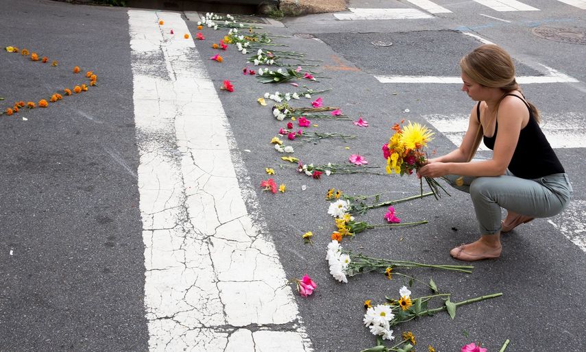Una mujer coloca flores en la esquina de la Fourth Street y Water Street, en Charlottesville, Virginia, donde un auto arremetió contra una multitud de personas este sábado 12 de agosto, con el saldo de tres personas muertas.