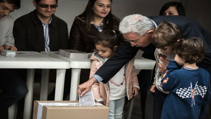 El senador colombiano Álvaro&nbsp;Uribe&nbsp;vota para la segunda vuelta de las elecciones presidenciales en compañía de sus nietos.