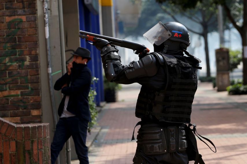 Un policía apunta una escopeta durante una protesta estudiantil en Bogotá, el sábado 23 de noviembre de 2019. Las autoridades colombianas mantienen una acentuada presencia policial y militar en la capital del país tras dos días de disturbios. 