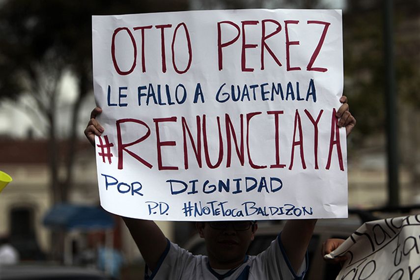 Un manifestante sostiene un cartel durante una protesta frente al Palacio Nacional en Ciudad de Guatemala donde piden la renuncia del presidente Otto Pérez Molina. (EFE)