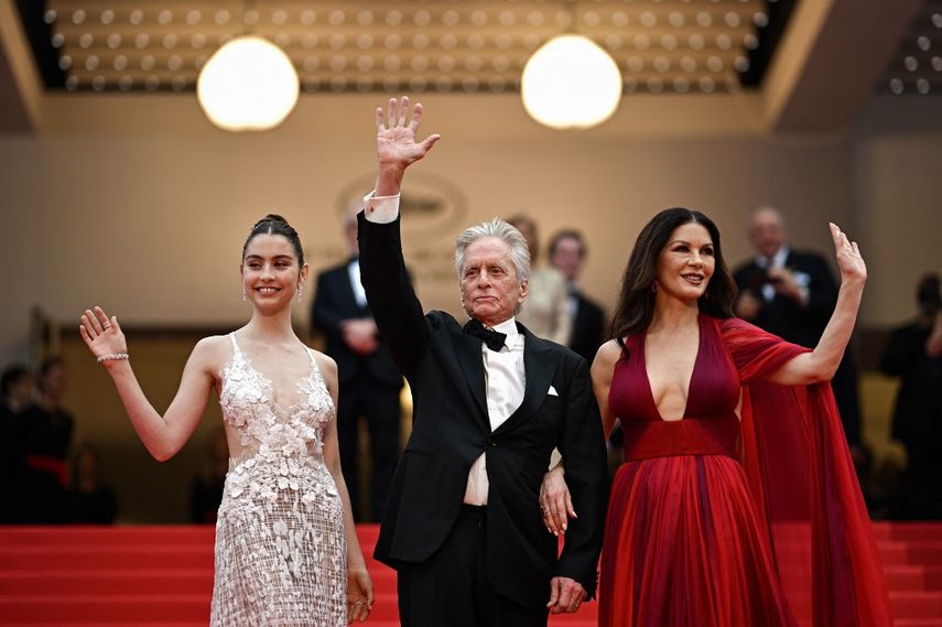 El actor estadounidense Michael Douglas saluda cuando llega con su esposa, la actriz británica Catherine Zeta-Jones y su hija Carys para la ceremonia de apertura y la proyección de la película "Jeanne du Barry" durante la 76ª edición del Festival de Cine de Cannes, en donde recibirá la Palma de Oro Honoraria.