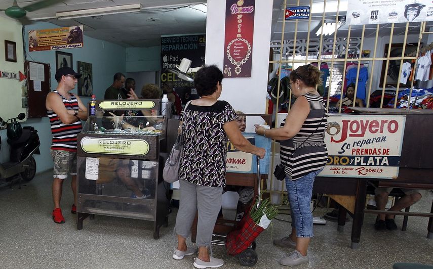 Varias personas arreglan relojes en su negocio privado en La Habana, Cuba.