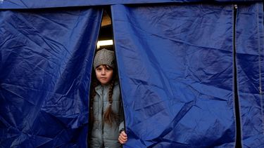 Una niña ucraniana mira desde una tienda de campaña mientras espera su reubicación después de cruzar la frontera entre Ucrania y Rumania en Siret, en el norte de Rumania, el 19 de marzo de 2022.&nbsp;