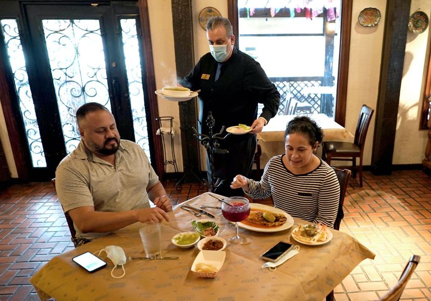 Un mesero atiende a una pareja en un restaurante de comida mexicana.