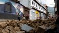 Personas caminan frente al muro derrumbado de una casa durante una serie de sismos en Santa María de Jesús, Guatemala, el 9 de julio de 2025.  