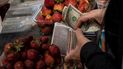 Una mujer guarda su cambio en billetes de un dólar después de comprar fruta en un puesto del mercado municipal de Quinta Crespo en Caracas, Venezuela.